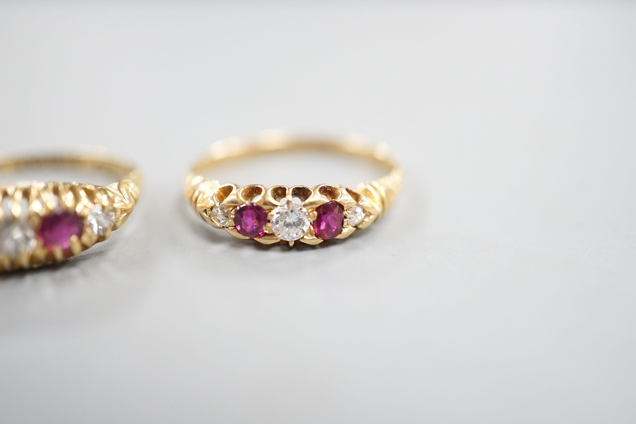 Two early 20th century 18ct gold, ruby and diamond five stone set half hoop rings, sizes m and P/Q, gross weight 5.1 grams.